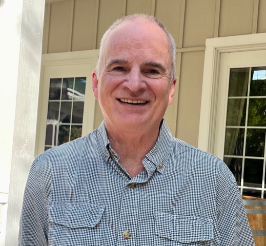 Photo of man standing outside of the Veritas Tasting Room entrance in a checkered button up shirt. 