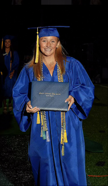 Photo of a high school graduate in a royal blue cap and gown holding her diploma. 