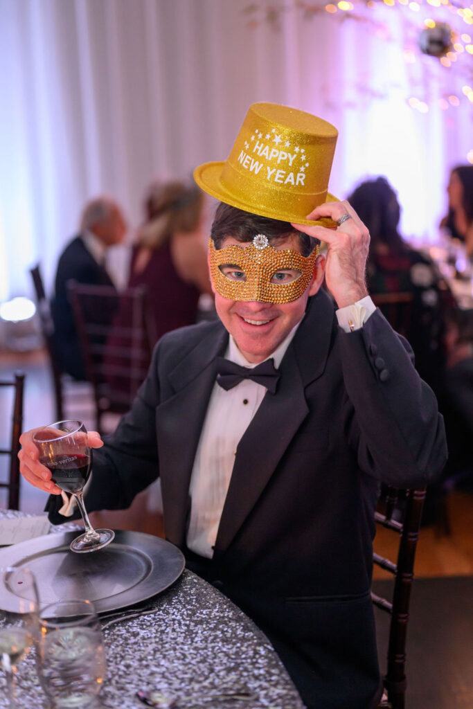 A man cheering with his glass of wine at the Veritas NYE Masked Ball
