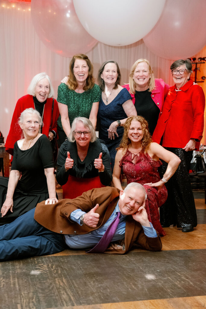 A group of people poses for a photo in a ballroom with large balloons in the background.