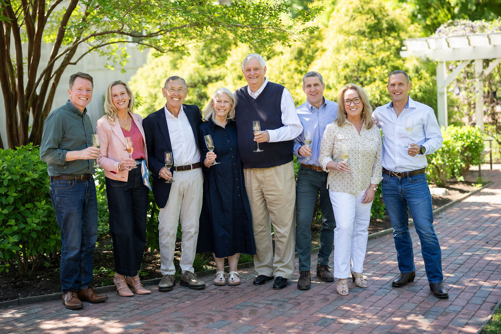 A group of 8 people stand in front of the entrance to Veritas Vineyard & Winery.